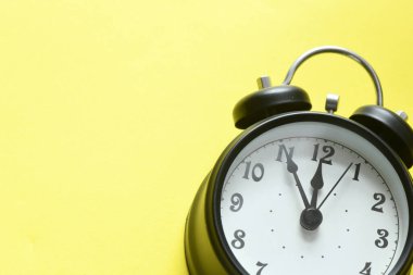 Sarı zemin üzerinde siyah alarm saati.