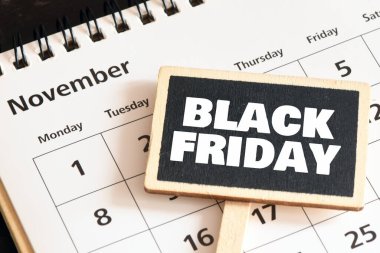 Kara Cuma kelimeleri bir takvime yerleştirilmiş küçük bir tebeşir tahtasında. Kasım, mağazalarda ve internette tanıtım süresidir..