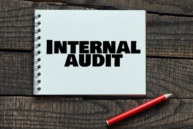 Tahta bir masadaki deftere yazılan INTERNAL AUDIT kelimeleri.