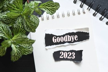 GOODBYE 2023 Küçük siyah kağıt parçaları üzerinde kelimeler.