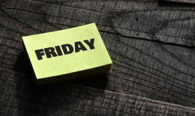 Küçük bir kağıt parçası ve ahşap masa üzerinde Cuma kelimesi.