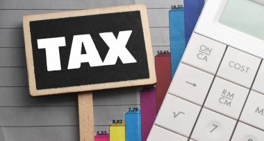 Hesap makinesinin yanında küçük bir tebeşir tahtasında vergi kelimesi var. Vergi İş Konsepti .