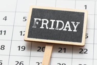 Bir takvime yerleştirilmiş küçük bir tebeşir tahtasındaki Cuma kelimesi.