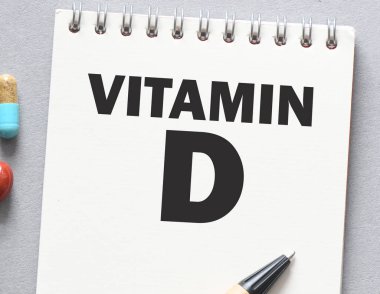 İlaç ve steteskopun yanında bir defterde VITAMIN D sözcükleri.