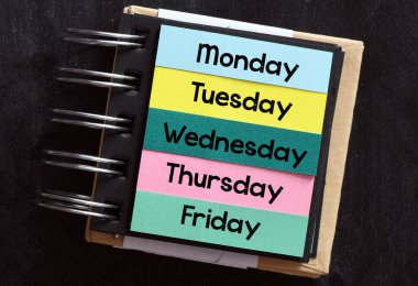 Pazartesi, salı, çarşamba, perşembe, cuma, haftanın her günü siyah arka planda bir defterde..