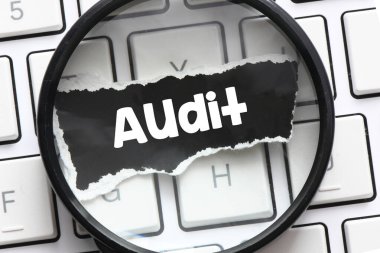 Büyüteçin altındaki siyah bir kağıtta AUDIT kelimesi.