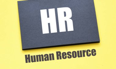 HR - Siyah bir kağıt ve sarı bir arkaplan üzerindeki İnsan Kaynakları kelimeleri.