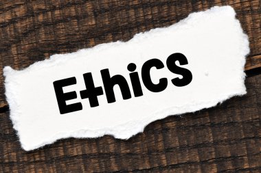 Küçük bir kağıt parçası ve ahşap bir masa üzerinde ETHICS. 