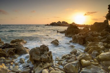 Turkuvaz suları, kumlu bir plaj, kayalık kıyı şeridi ve açık mavi gökyüzü içeren nefes kesici Kıbrıs Akdeniz manzarası. Yaz tatilleri, turizm ve doğa aşıkları için mükemmel bir tatil yeri..
