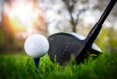 Golf topu ve golf sopası güzel golf sahasında, gün batımında.