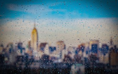 Şehir manzaralı pencereye yağmur damlaları, arka planda New York.