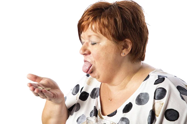 Pięćdziesięcioletnia Kobieta Trzymająca Tabletki Ręce Wystającym Językiem Odizolowana Białym Tle — Zdjęcie stockowe