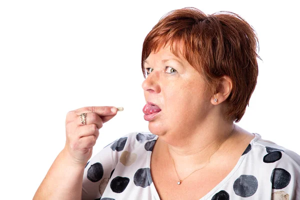 50歳の太りすぎの女性が錠剤を持ち 舌を出し 白い背景に隔離された — ストック写真