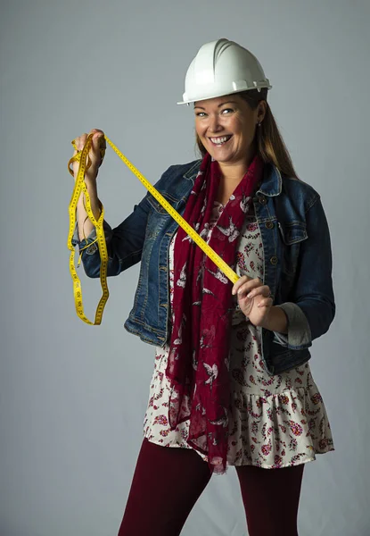 四十来岁的女人 穿着时髦的波希米亚服装 头戴硬礼帽 手里拿着一条尺寸为黄色的带子 免版税图库图片