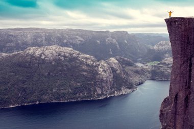 Kız ellerini kaldırdı Lysefjord 'un üzerinde duran ünlü Preikestolen Minpit Rock' ın üzerinde