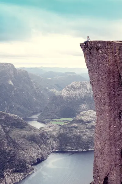 Oğlan, Lysefjord 'un üzerindeki ünlü Preikestolen Minpit Rock' ta oturuyor.