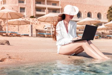 Kumda dizüstü bilgisayarı olan bir kadın dinleniyor ve serbest çalışıyor.