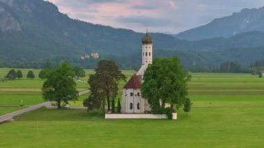 Neuschwanstein şatosu yakınlarındaki Saint Coloman Kilisesi 'nin insansız hava aracı eşliğinde Almanya' nın Bavyera eyaletindeki Schwangau dağlarının arka planına karşı.