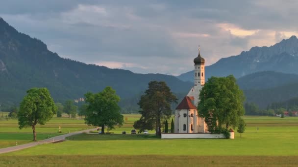 ノイシュヴァンシュタイン城近くの聖コロマン教会のドローンビュー 美しい山の背景に対して ドイツのバイエルン州シュワンガウ — ストック動画