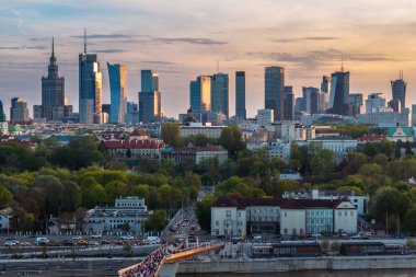 Warszawa, Polonya - 9 Nisan 2024: Varşova şehir merkezinin panoramik manzarası, yeni açılan yaya ve bisiklet köprüsünün modern şekli tarafından çerçevelenmiş, canlı bir anıt ve modern gökdelenler karışımına sahip..