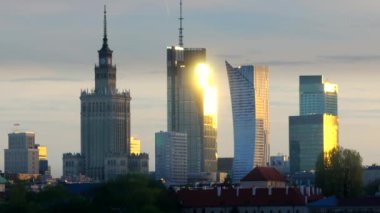 Warszawa, Polonya - 9 Nisan 2024: Varşova şehir merkezinin panoramik manzarası, yeni açılan yaya ve bisiklet köprüsünün modern şekli tarafından çerçevelenmiş, canlı bir anıt ve modern gökdelenler karışımına sahip..