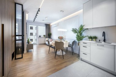 Parlak bir yemek alanı ve minimalist mutfak tasarımı içeren modern açık planlı bir daire..