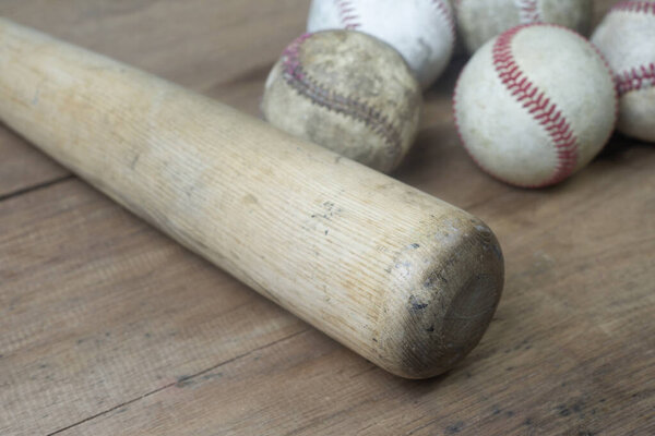 Close up old baseball and wooden bat on a wooden table. select focus.