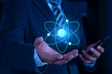 İşadamı mavi arka planda yaratıcı atomu tutuyor. Nükleer füzyon konsepti, sonsuz enerji, ucuz elektrik, gelecekteki teknolojiler. Bilim ve gelecek kavramı 