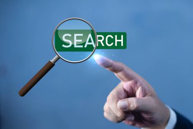 İş adamının eli büyüteç arama kelimesine dokunuyor. Sanal ekranda iş bilgileri arayan bir işadamı