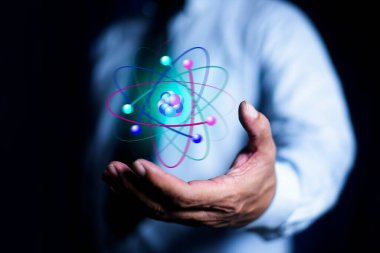 İşadamı yaratıcı atomu tutuyor. Nükleer füzyon konsepti, sonsuz enerji, ucuz elektrik, gelecekteki teknolojiler. Bilim ve gelecek kavramı
