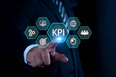 KPI İş Konsepti için Anahtar Performans Göstergesi. Holografik simgeler olarak gösterilen anahtar performans göstergelerini (KPI) analiz etmek için veri ile çalışan işadamı
