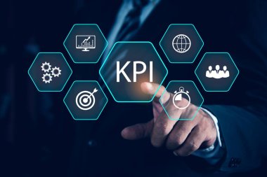 KPI İş Konsepti için Anahtar Performans Göstergesi. Holografik simgeler olarak gösterilen anahtar performans göstergelerini (KPI) analiz etmek için veri ile çalışan işadamı