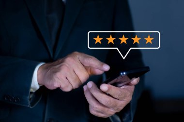 İyi derecelendirme, memnuniyet, iyi deneyim, müşteri değerlendirmesi, müşteri geribildirim kavramını değerlendirmek için beş yıldızlı cep telefonu kullanan iş adamı eli