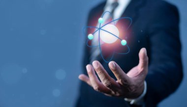 İşadamı bir atomun molekülünü tutuyor. Nükleer füzyon konsepti, sonsuz enerji, ucuz elektrik, gelecekteki teknolojiler. Bilim ve gelecek kavramı