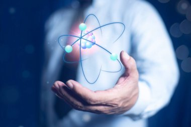 İşadamı bir atomun molekülünü tutuyor. Nükleer füzyon konsepti, sonsuz enerji, ucuz elektrik, gelecekteki teknolojiler. Bilim ve gelecek kavramı