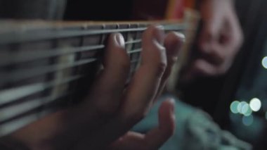 Gitar çalıyorum. Akustik gitar tıngırdatıyorum. Müzisyen müzik çalar. Erkek parmakları arabulucuyu tutuyor. Karanlık odada gitar çalan bir adam eli. Tanımlanamayan kişi prova yapıyor, fretboard yakın plan.