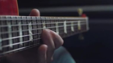 Gitar çalıyorum. Müzisyen müzik çalar. Erkek parmakları arabulucuyu tutuyor. Karanlık odada gitar çalan bir adam eli. Tanımlanamayan kişi prova yapıyor, fretboard yakın plan.