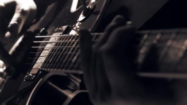 Gitar çalıyorum. Akustik gitar tıngırdatıyorum. Müzisyen müzik çalar. Erkek parmakları arabulucuyu tutuyor. Karanlık odada gitar çalan bir adam eli. Tanımlanamayan kişi prova yapıyor, fretboard yakın plan.