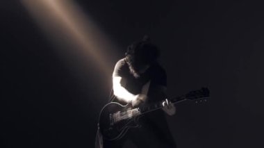 Genç bir adam elektro gitar çalıyor..