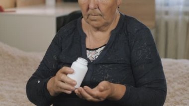 Emekli kadın, odada oturan yaşlı kadın bir doktor tarafından yazılan ilaç ve hapları kullanıyor..