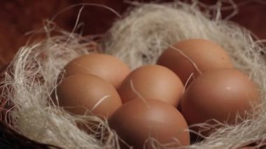 Saman üstünde taze organik yumurta. Güneşli bir sabahta çiftlikte tavuk yumurtalı yuva. Çiftçiler kahvaltı için yumurta toplarlar. Bir çiftçi çiftlikteki tavuk kümesinde taze tavuk yumurtası toplar..