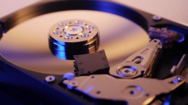 Parçalanmış sabit disk çalışıyor, dönüyor, bilgi okuyor. Bilgisayarın yedek parçaları. Hafıza aygıtları. Beyaz bir arkaplanda.
