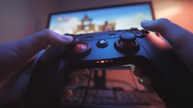 Joystick. Bir oyuncunun elleri. Genç oyuncu bir joystick ile bir video oyunu oynuyor. Akşamları elinde joystick olan bir elin yakın çekimi. Ekranın önündeki joystick.