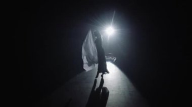 Spot ışıklarıyla modern dans eden bir kadın. Çağdaş dans. Genç dansçı karanlık sahnede oynuyor. 4K 'da yakın plan, UHD