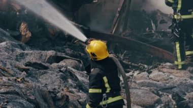 İtfaiyeci ateşle savaşmak için yangın hortumu kullanıyor..