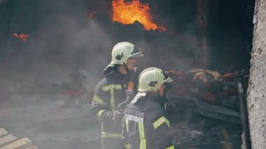 İtfaiyeci ateşle savaşmak için yangın hortumu kullanıyor..