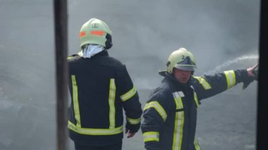 İtfaiyeci ateşle savaşmak için yangın hortumu kullanıyor..