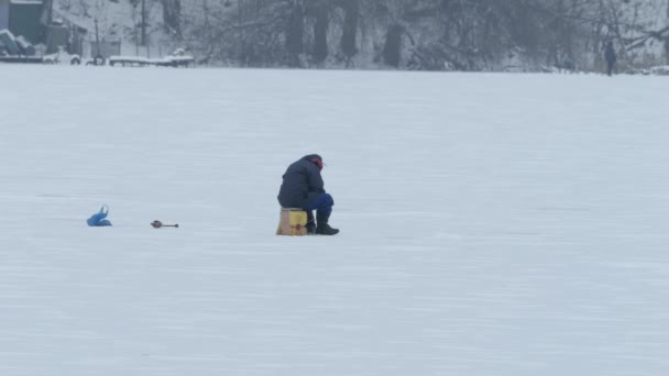 冰上钓鱼在冰上钓鱼的人想捕鱼 冬天在寒冷的日子钓鱼 冬季活动 湖上的渔夫 — 图库视频影像