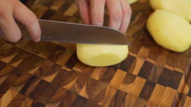 Patates soymak. Patates soyan insanların elleri. Bir adam manuel patates soyucusuyla çiğ patates soyar. Patates soymak ve soymak. Mutfakta yemek pişirmek. Vejetaryen yemeği. Yakın plan. Üst görünüm