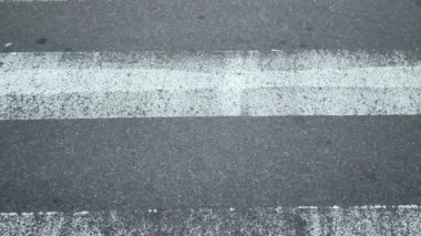 Gri asfalt üzerindeki yol işaretlerinin beyaz çizgileri hareket eden bir arabadan görünüyor. Kazaları önlemek için güvenli trafik düzenlemesi yapılıyor. Trafik Kuralları.